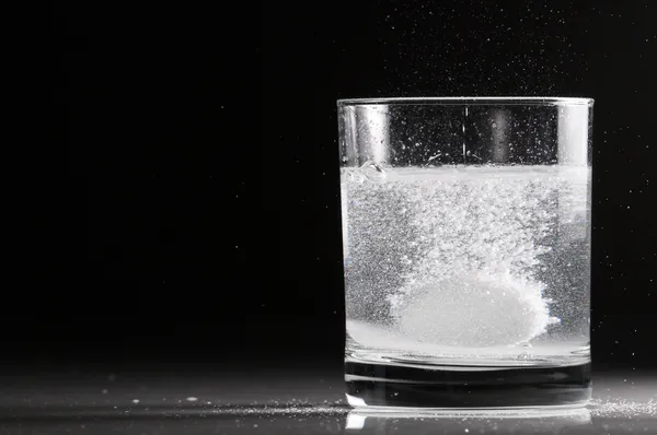 Gashoudende pil in een glas water Stockfoto