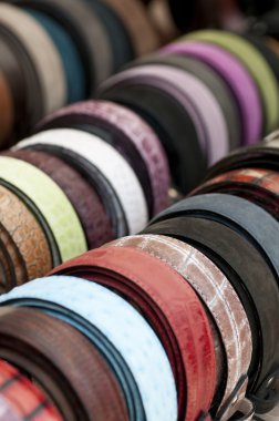 Leather belts of various colors on display clipart