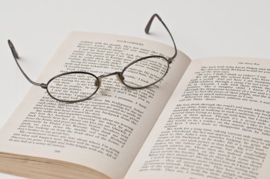 Glasses with black rounded frame on open book clipart