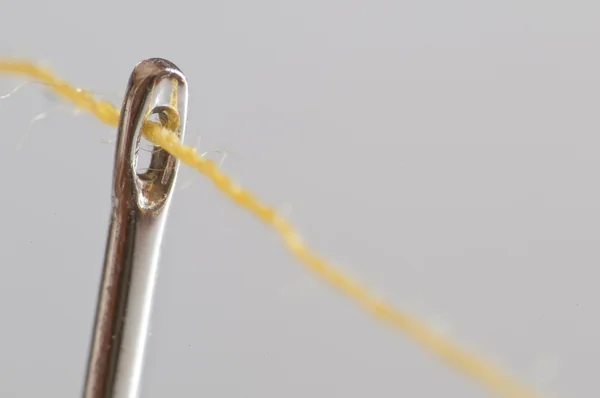 Yellow cotton thread through a needle eye — Stock Photo, Image