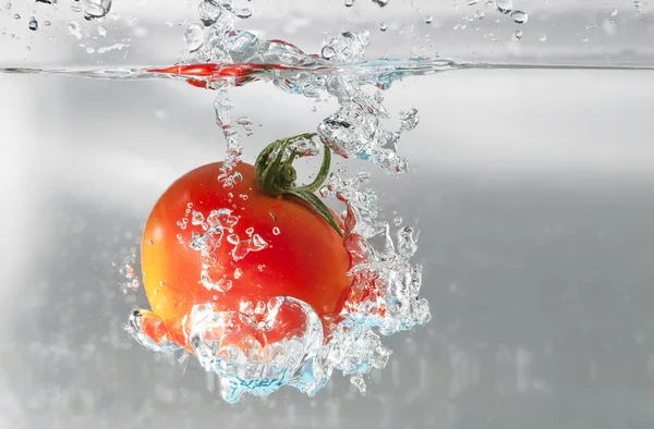 A cherry tomatoe dip into water — Stock Photo, Image