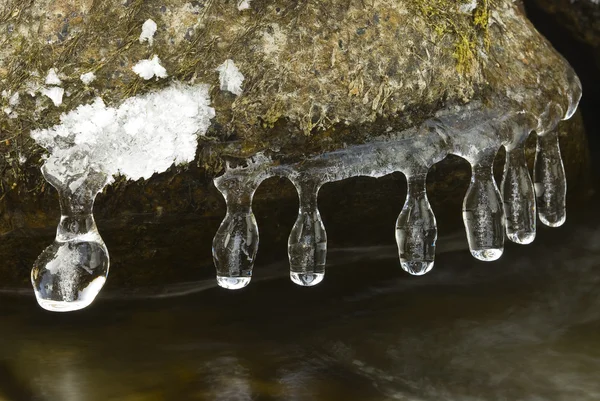 Hängande icecles bildar en sten över en flod — Stockfoto