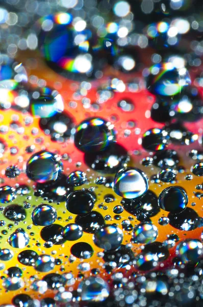 カラフルな反射面の上の水の滴 — ストック写真