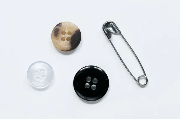 Κλειστό καρφίτσα ασφάλειας και λευκό, μαύρο και borwn κουμπιά σε λευκό φόντο — Φωτογραφία Αρχείου