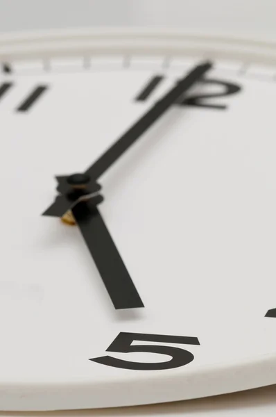 Weiße Uhr mit schwarzen Zeigern bei fünf Uhr — Stockfoto