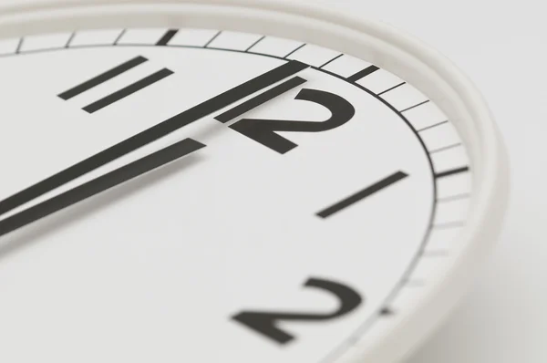 Orologio bianco con lancette nere che mostrano un minuto a mezzanotte, mezzogiorno — Foto Stock