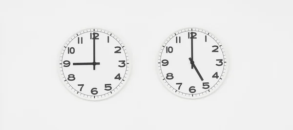 Hvit klokke med svarte hender som viser klokka ni til fem – stockfoto