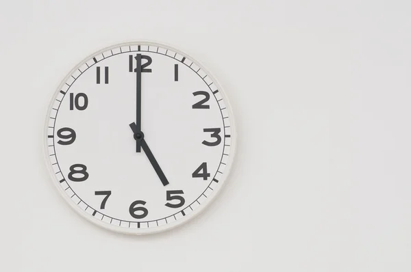 Vit klocka med svarta händer visar klockan fem — Stockfoto
