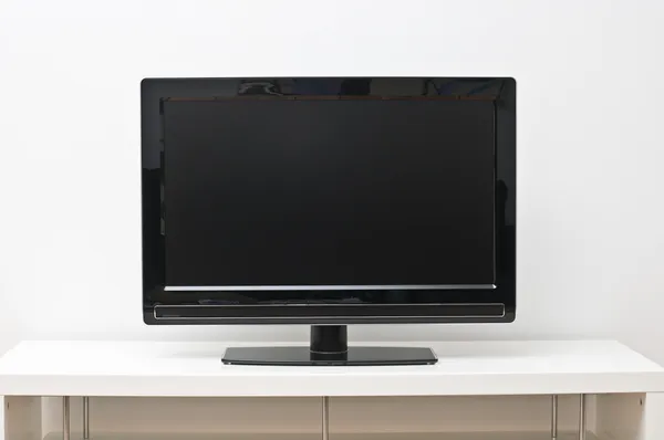 Black flat screen tv set on white table and wall — Stock Photo, Image