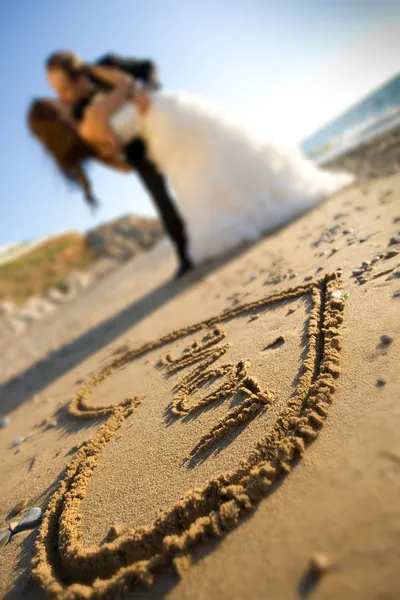 Счастливая пара и песок любви — стоковое фото