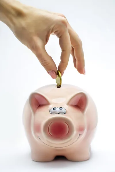Hand is het invoegen van een munt in roze piggy bank — Stockfoto