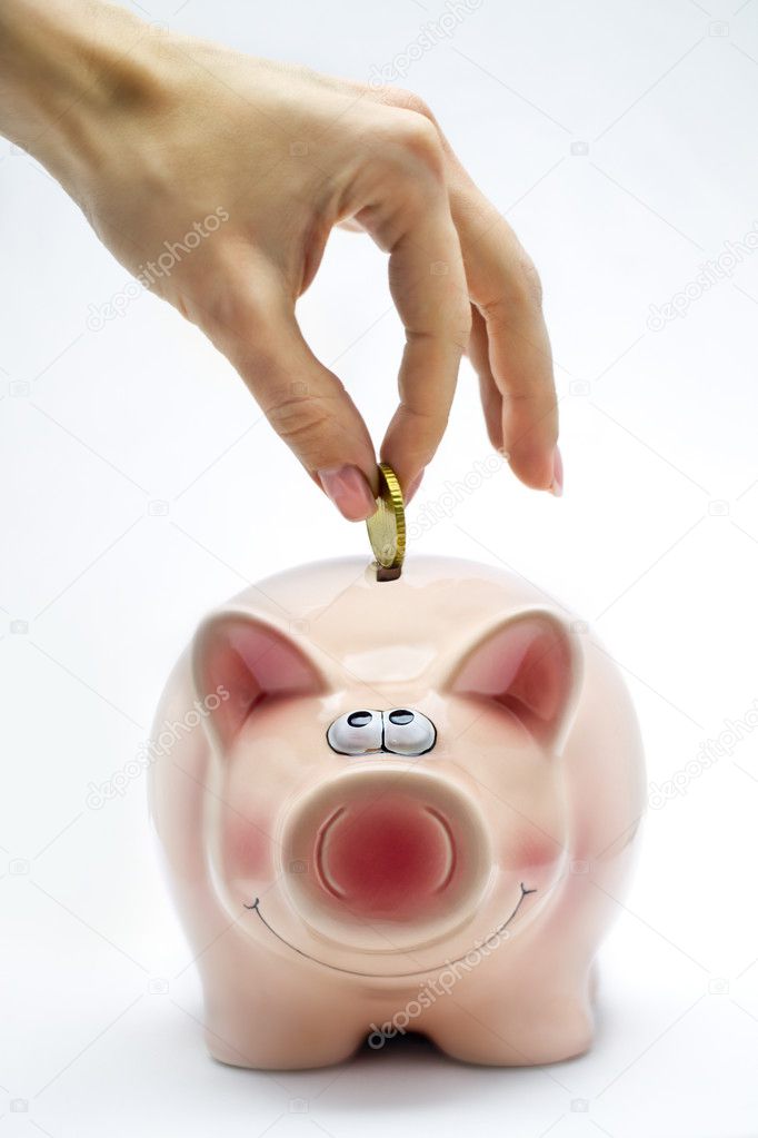 Hand is inserting a coin into pink piggy bank