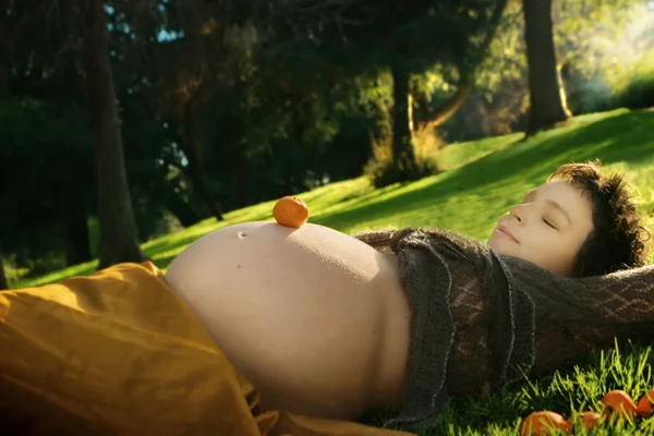 Mulher grávida deitado na grama — Fotografia de Stock