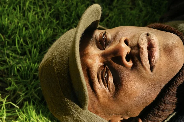 Close-up de homem afro-americano deitado na grama — Fotografia de Stock