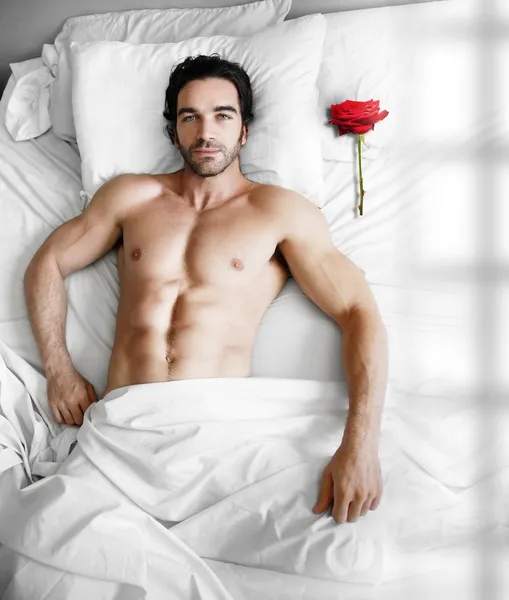 Homem na cama com rosa — Fotografia de Stock