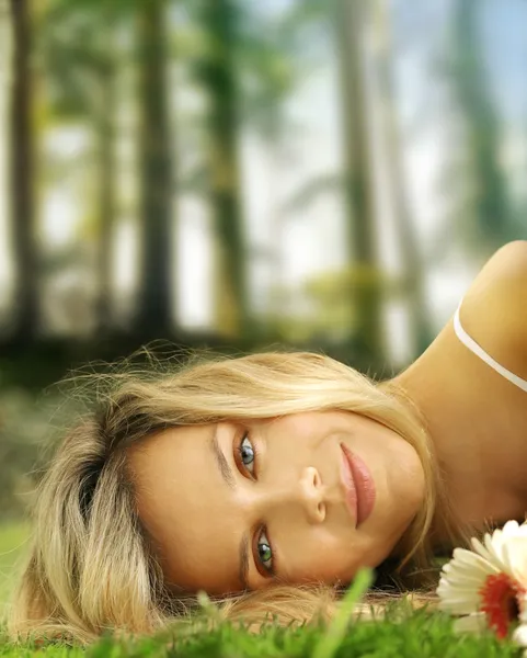 Söt flicka och blommor i gräset — Stockfoto