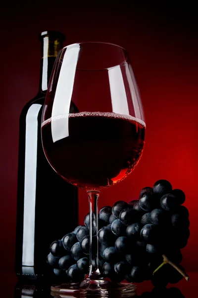 Una copa llena de vino y botella — Foto de Stock