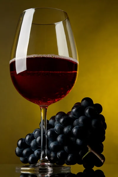 Una copa de vino tinto y uvas — Foto de Stock