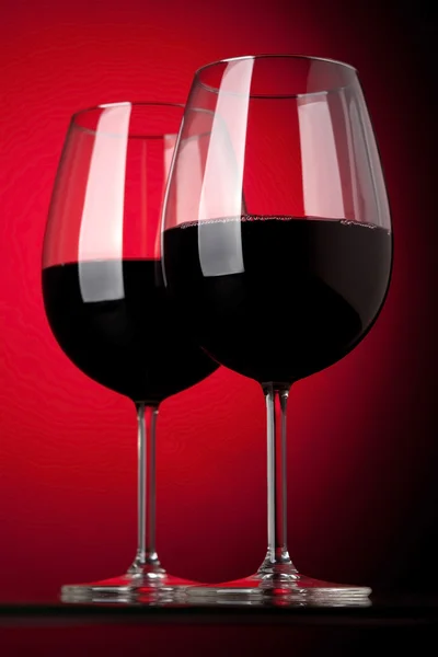 Twee glazen van rode wijn op een rode achtergrond — Stockfoto