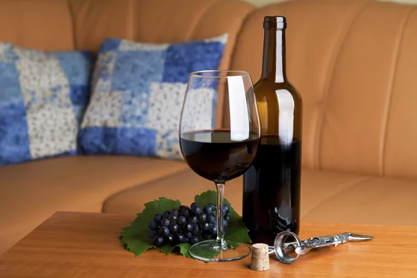 A glass wine with a bottle of red wine on table — Stock Photo, Image