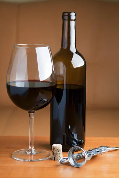 Een glas wijn met een fles rode wijn op tafel — Stockfoto