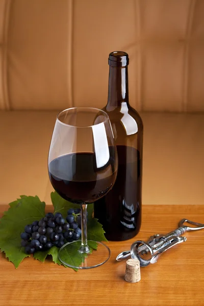 A glass wine with a bottle of red wine on table — Stock Photo, Image