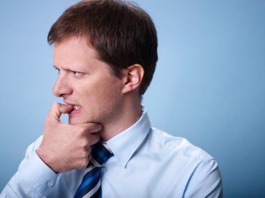 Nervous business man biting finger nails clipart