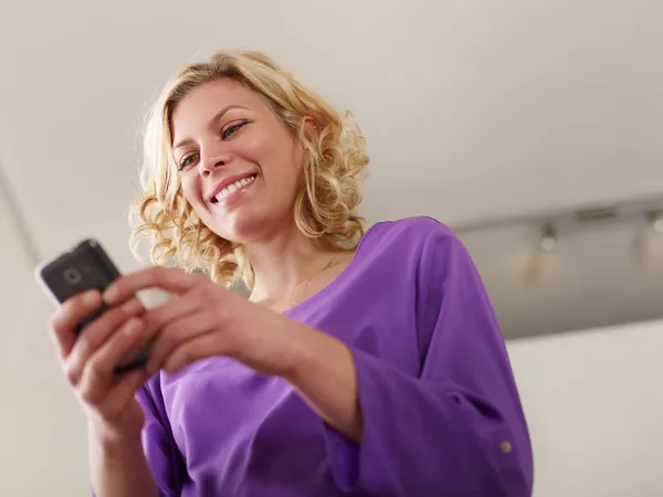 Счастливая молодая женщина печатает смс на мобильный телефон — стоковое фото