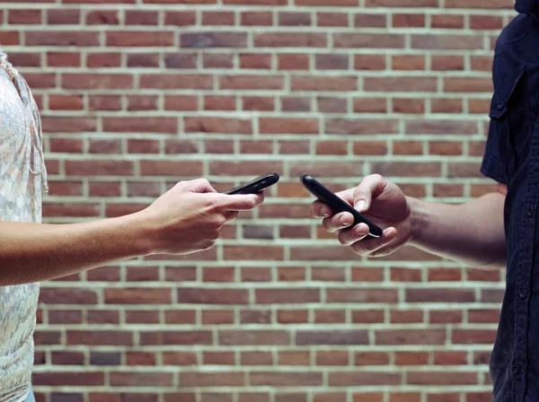 Мужчина и женщина используют мобильные телефоны для обмена файлами — стоковое фото