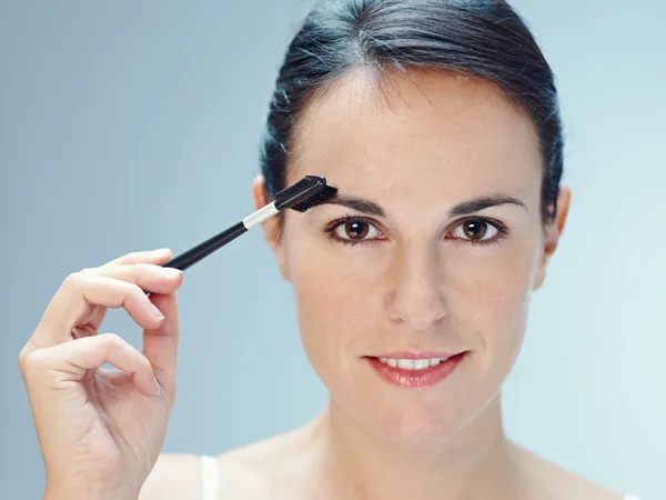 Vrouw aanbrengen van make-up met borstel — Stockfoto