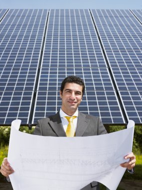 Businessman standing near solar panels clipart