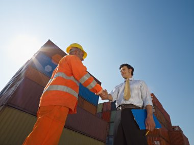 Businessman and manual worker with cargo containers clipart