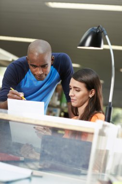 Two students reviewing essay in library clipart