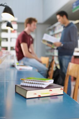 Book and notepads on desk in library clipart