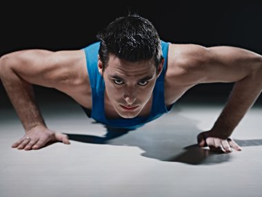 Man doing push-ups on black background clipart