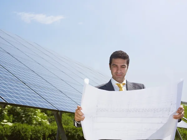 Επιχειρηματίας που στέκεται κοντά σε ηλιακούς συλλέκτες — Φωτογραφία Αρχείου