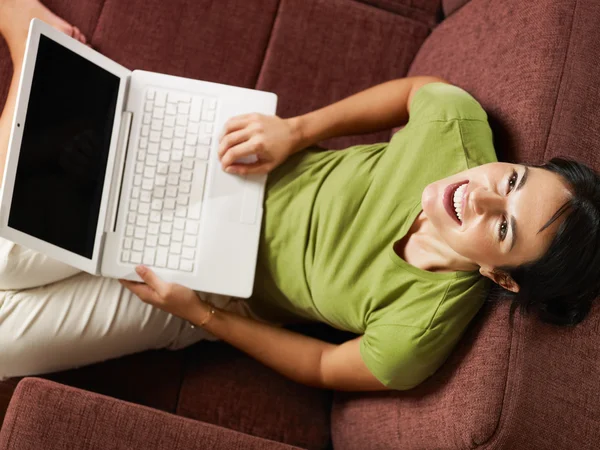 Frau mit PC lacht auf Sofa — Stockfoto