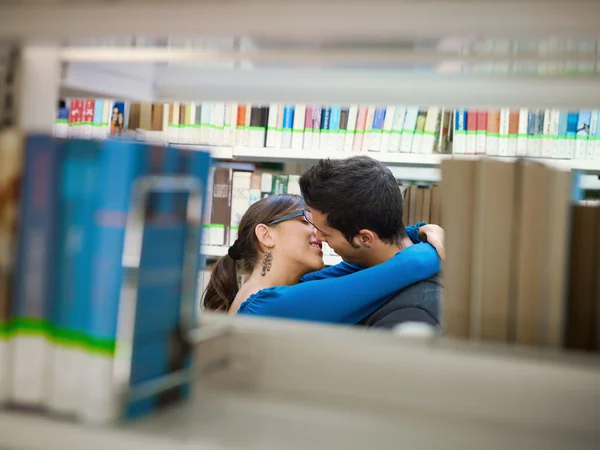 Studenten küssen sich in Bibliothek — Stockfoto