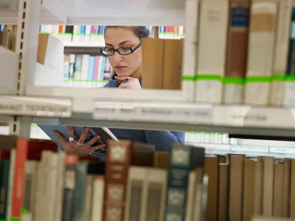 Vrouw kiezen boek in bibliotheek — Stockfoto