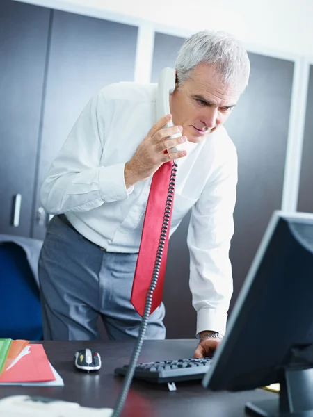 Зрелый бизнесмен на телефоне в офисе — стоковое фото