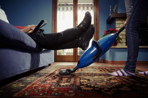 Mann entspannt sich, während Frau zu Hause Hausarbeiten erledigt — Stockfoto