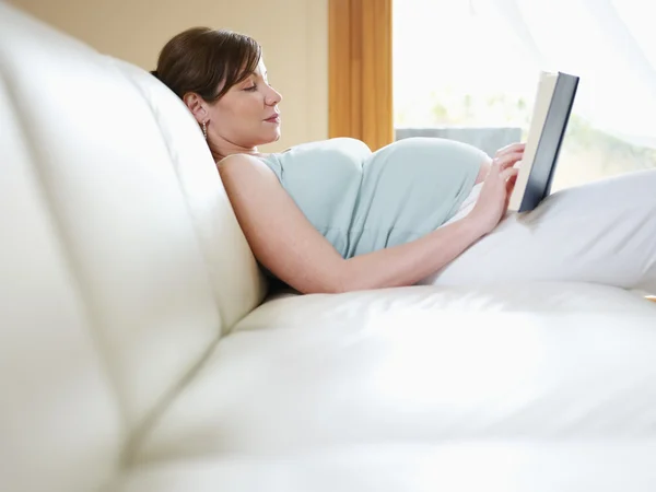 Έγκυος γυναίκα που διαβάζει το βιβλίο στο σπίτι — Φωτογραφία Αρχείου