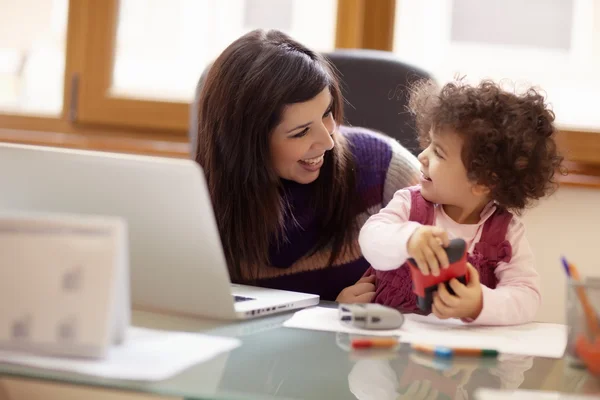 Multitasking mother with her daughter — Stock Photo, Image