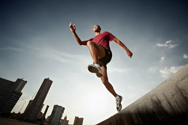 Homem hispânico correndo e pulando de uma parede — Fotografia de Stock