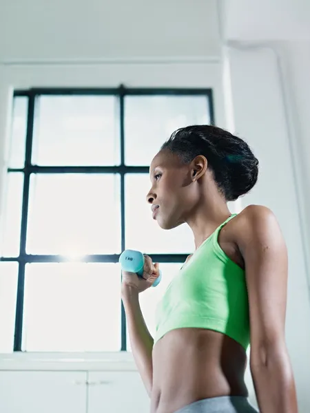 Afrikansk kvinna tränar med små vikter i gymmet — Stockfoto
