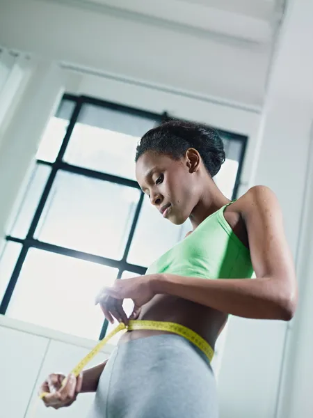 测量用黄色胶带腰的非洲女人 — 图库照片