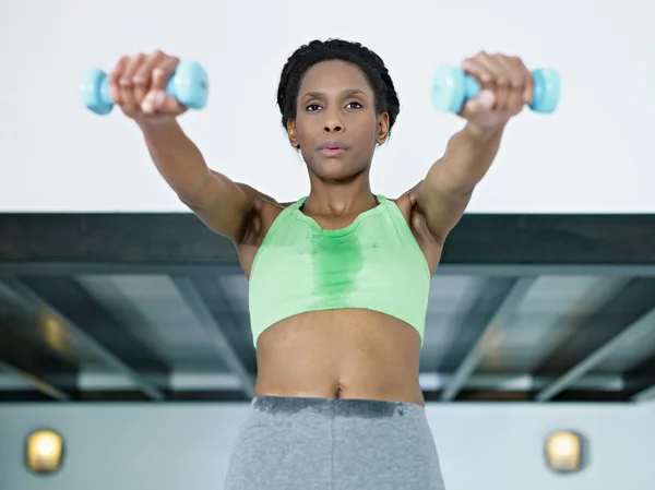 Afrikansk kvinna tränar med små vikter i gymmet — Stockfoto