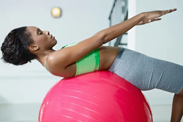 Mujer africana haciendo series de abdominales en el gimnasio — Foto de Stock