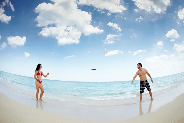 Junger glücklicher Mann und Frau spielt mit Frisbee — Stockfoto