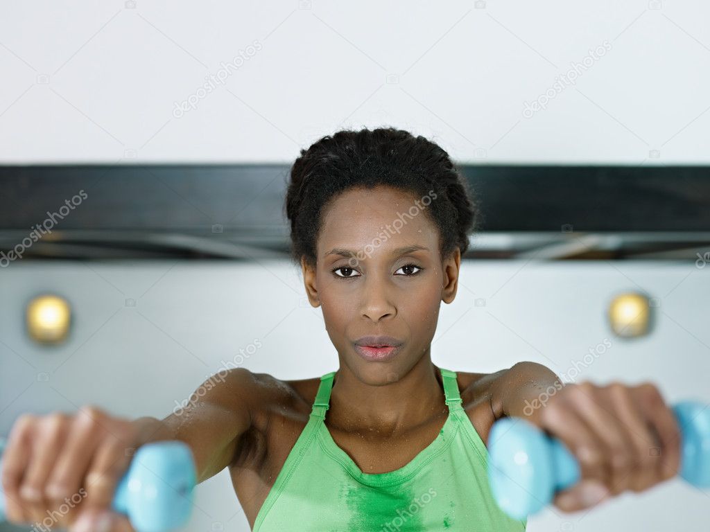 African woman exercising with small weights in gym